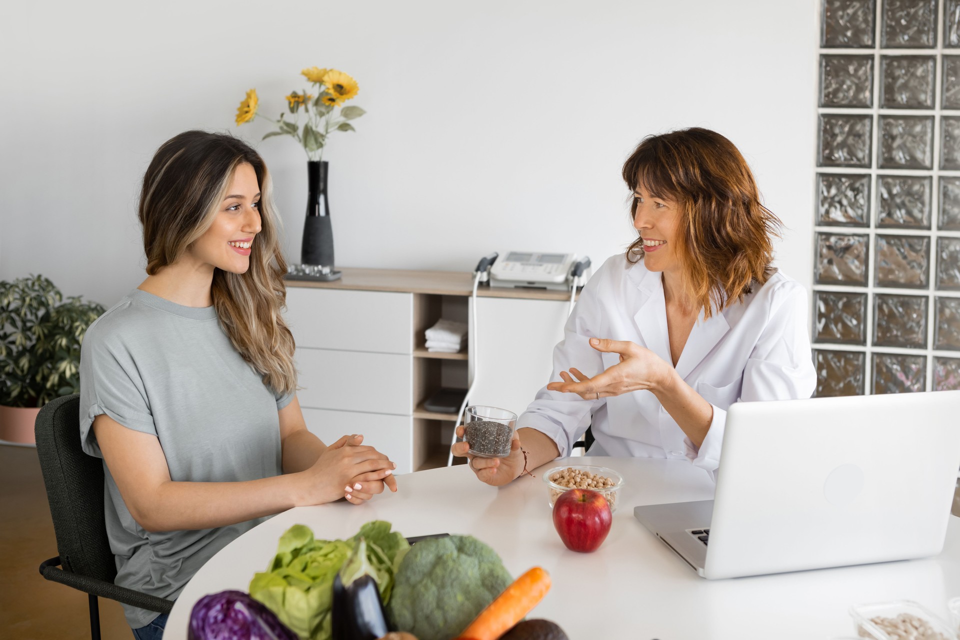 Nutritionist interacting with patient at table with healthy products indoors