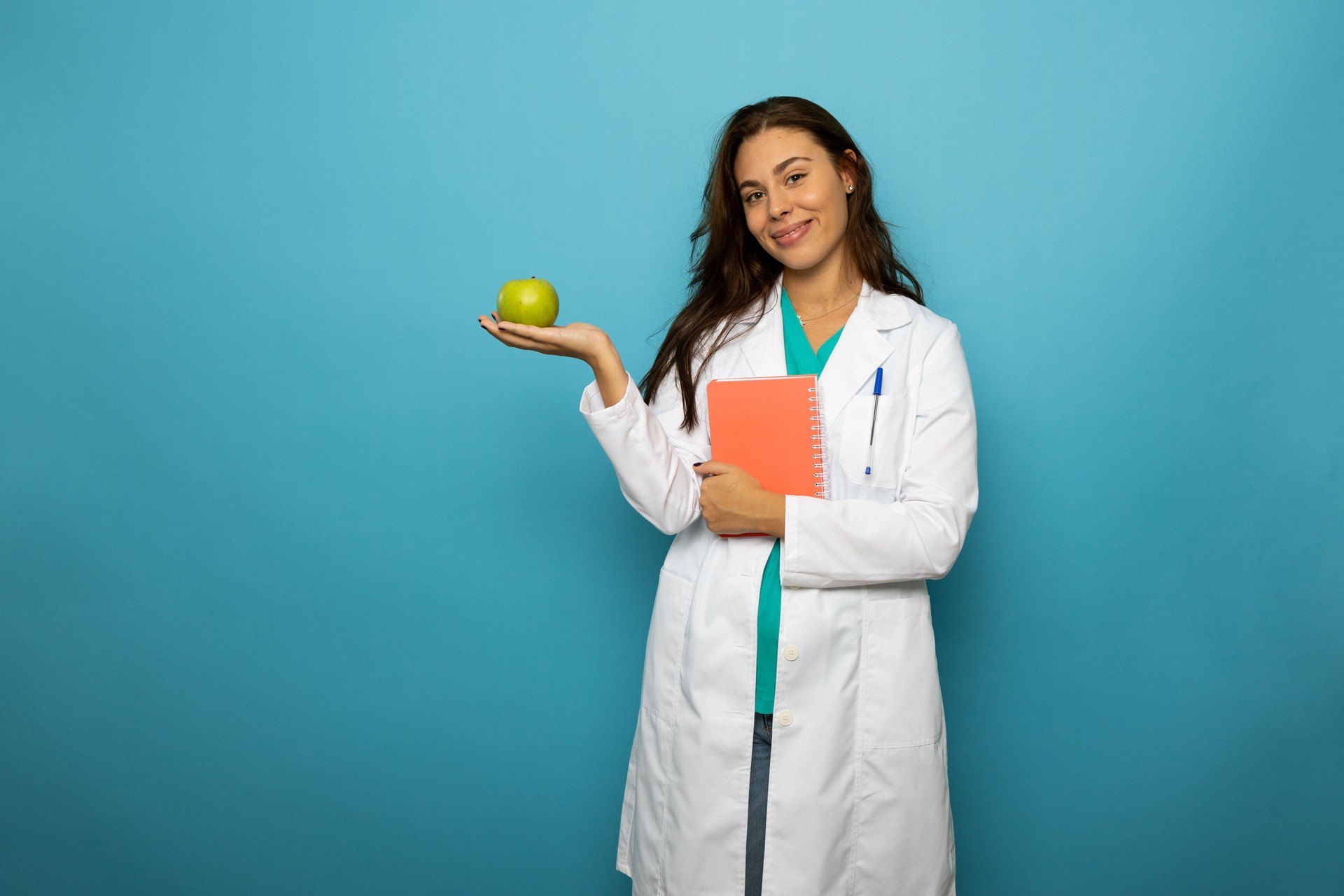 Female nutritionist promoting healthy eating habits with a green apple and notebook